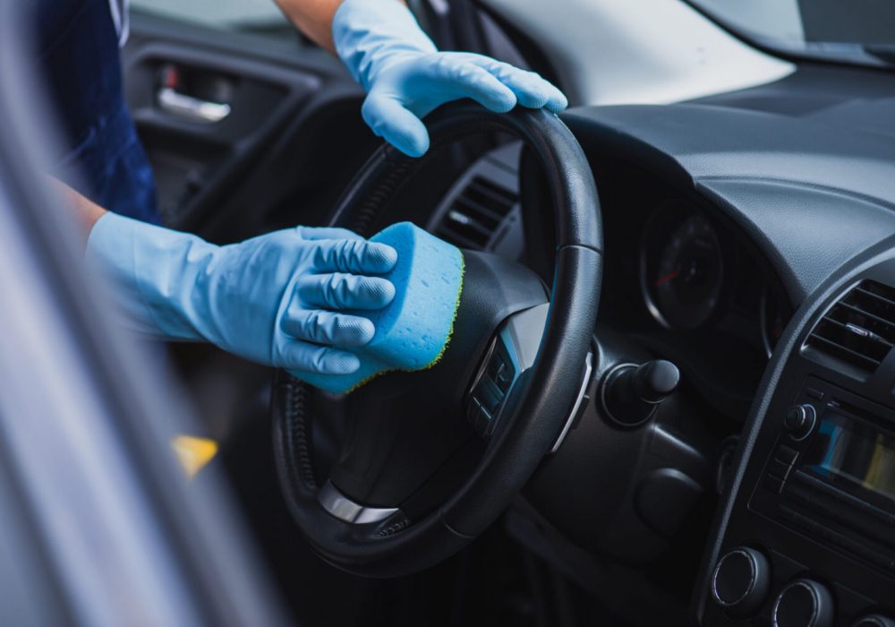 selective focus of car cleaner wiping steering wheel with sponge